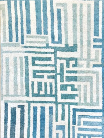 Close up of a Beni Ourain Moroccan Rug with a blue and white maze design.