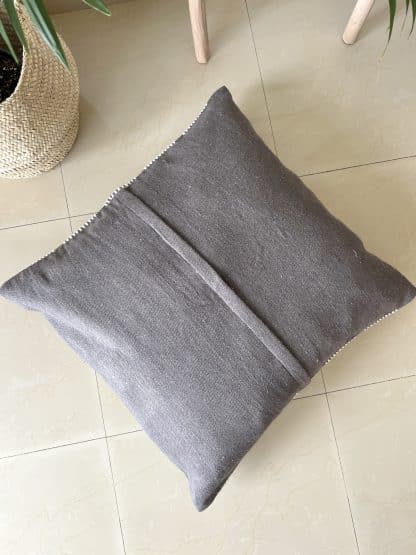 Upside down Moroccan floor pillow made with dark grey and off-white wool on a marble floor.