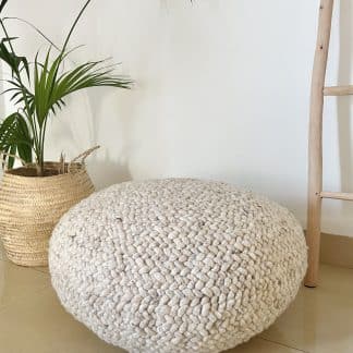 Beige Braided Pouf with a plant and wood ladder in the background.