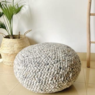Heather grey Braided Pouf with a plant and a wooden ladder in the background