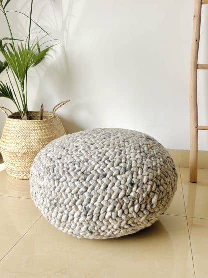 Heather grey Braided Pouf with a plant and a wooden ladder in the background