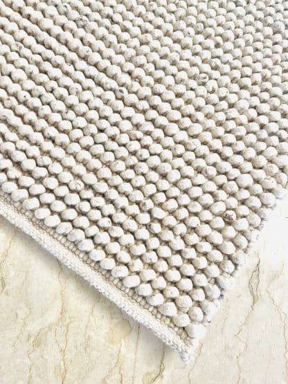 Aerial shot of the corner of a Handmade Moroccan rug Tapis de Boules in beige