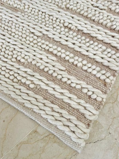 Aerial shot of the corner of a Tapis de Boules Ivory Wave rug.